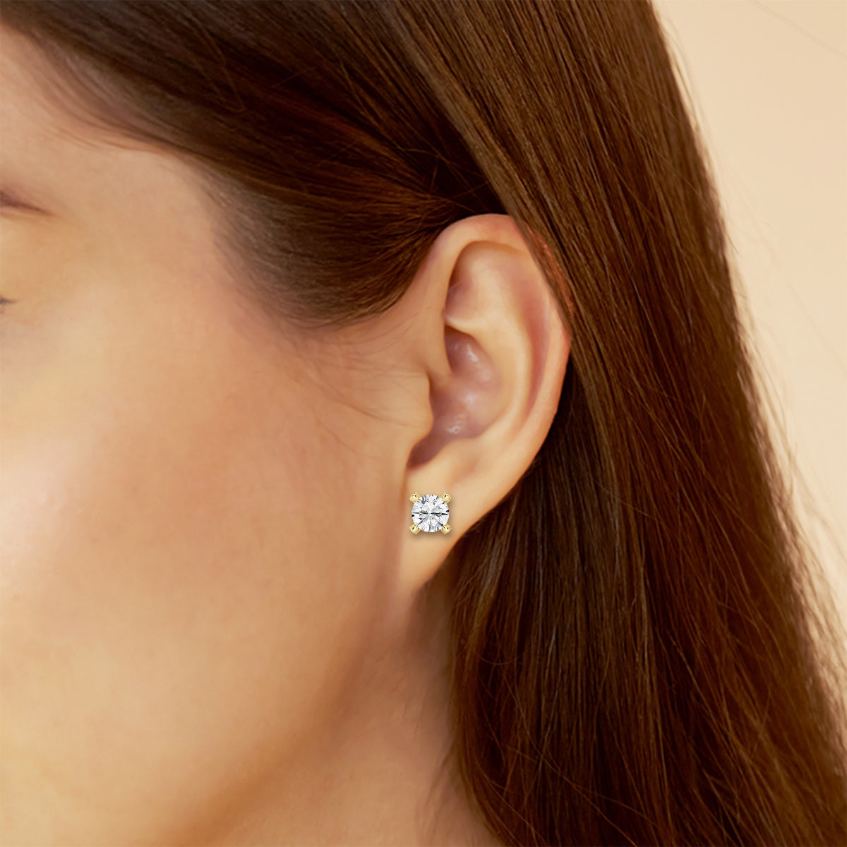 A 4-carat lab-grown diamond stud earring set in yellow gold on a woman's ear